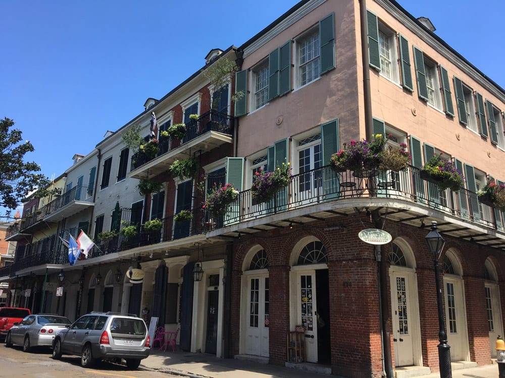 Colorful buildings line a street in the French Quater, all with stunning hanging baskets of flowers.