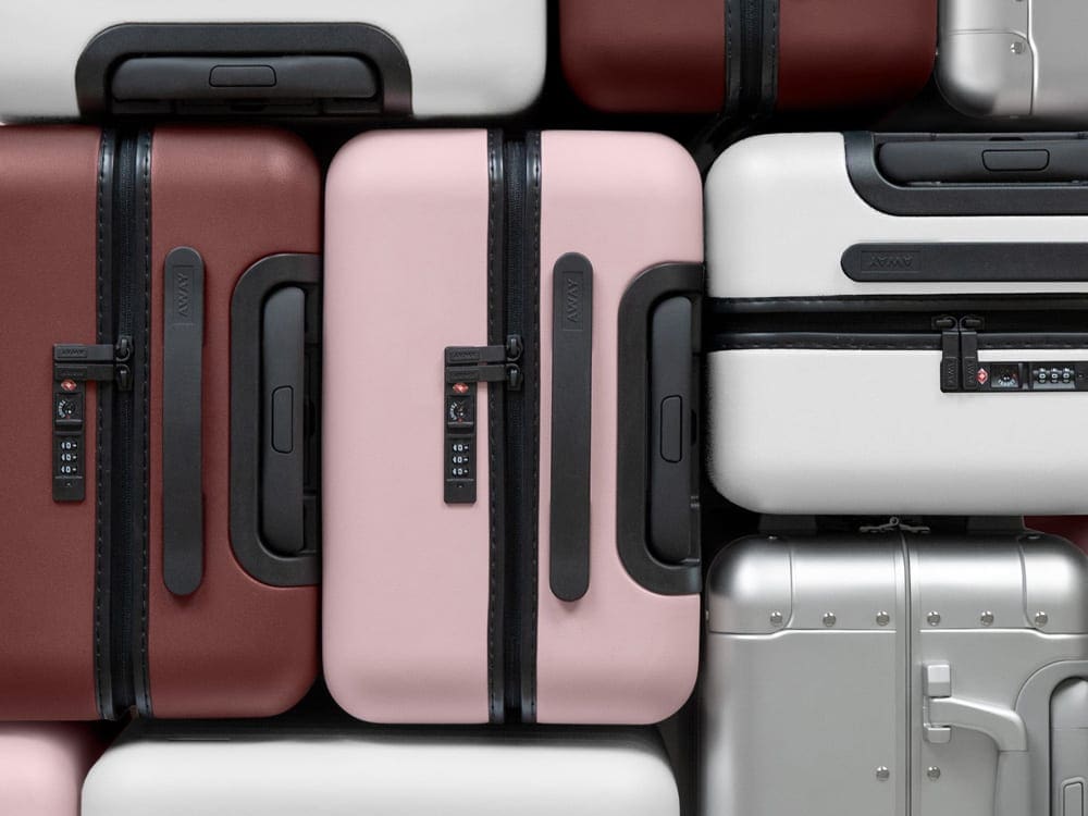 aerial view of hard-sided Away Travel Luggages in the colors red, silver, white, and pink. Away Travel has some of the best travel luggage for kids. 