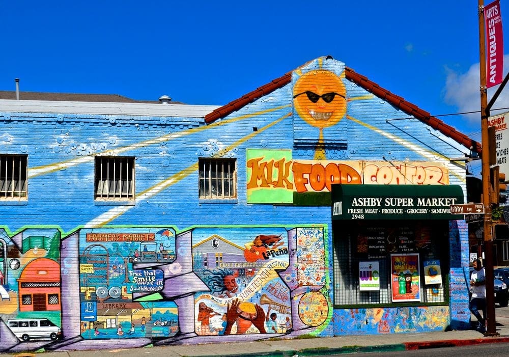 Street art on a building in Berkeley, CA, featuring bright colors and a variety of dibictions related to music, farming, and food.