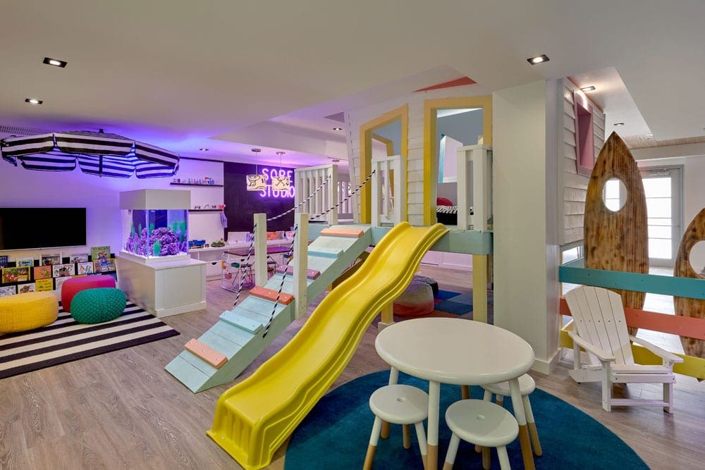 Inside the colorful kids club at Loews Miami Beach Hotel, featuring a table and stools and large slides.