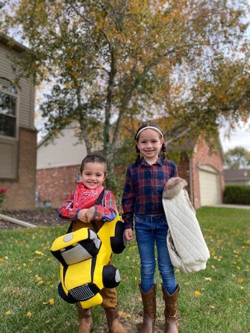 Two young kids are wear travel inspired costumes for Halloween, one as a truck, the other as a farmer.