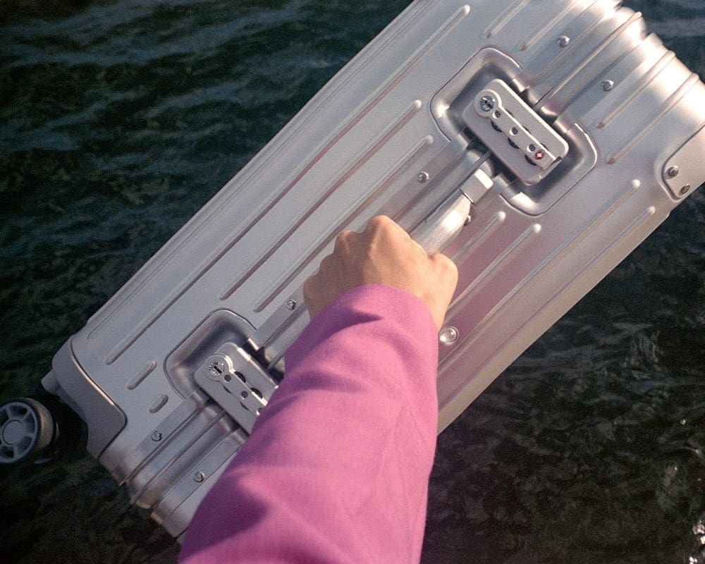 A woman's hand holding a silver suitcase, one of the best travel gifts for Mom this Christmas.