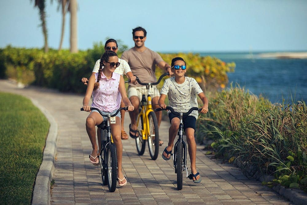 A family of four rides bikes along a path at South Seas Resort, one of the best family resorts in Florida.