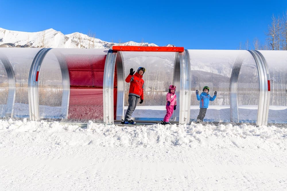 A parent and two kids walk within a large concorse at Telluride.