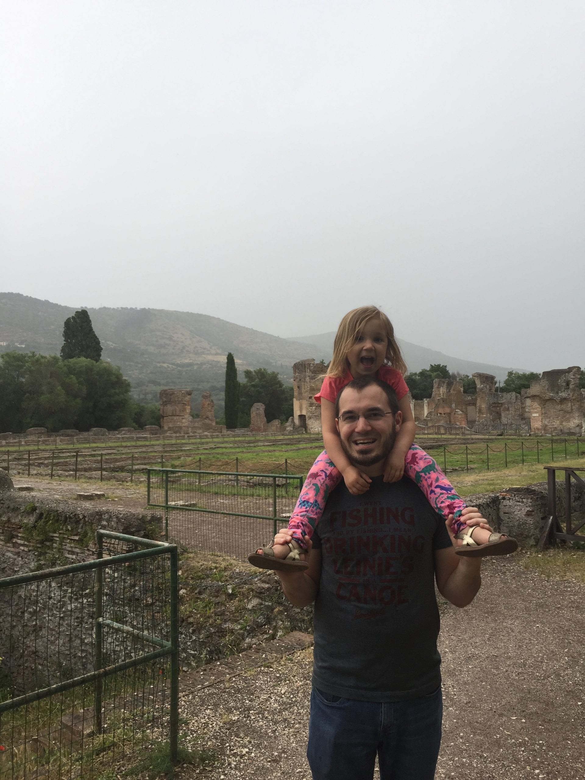 A young girl rides on her father's shoulder inside Hadrian's Villa near Rome, one of the best things to do Rome with toddlers.