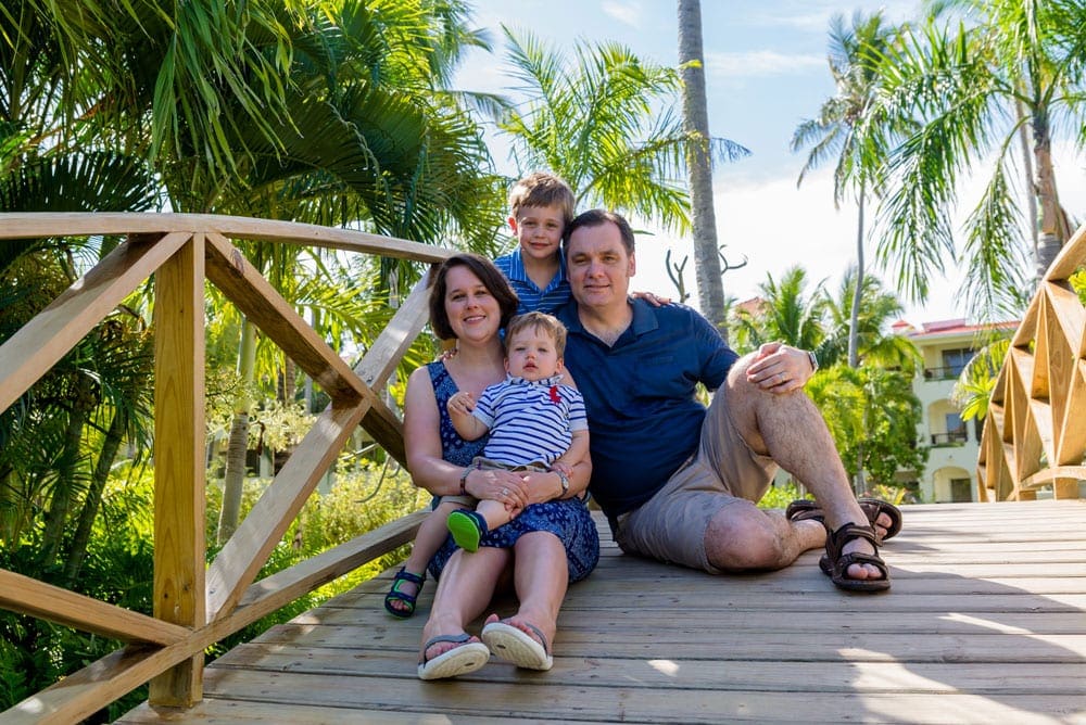 A family of four sits together on a bridge on a bright sunny day in the Dominican Republic.