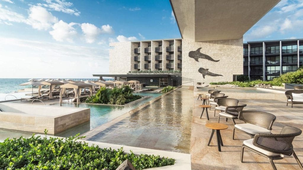 Inside the Grand Hyatt Playa del Carmen, featuring several seated areas, a pool, and a glimpse at the ocean access, one of the best resorts in Playa del Carmen.