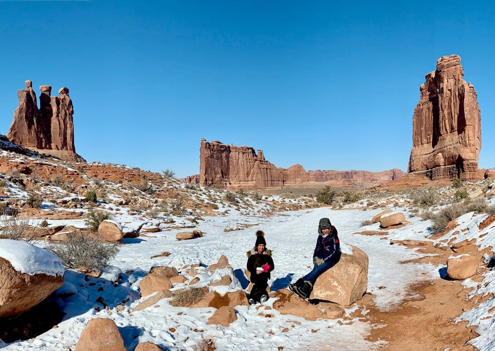 Two Kids sitting while hiking Park Avenue trail in Arches National Park, one of the best budget-friendly Christmas destinations in the US for families.