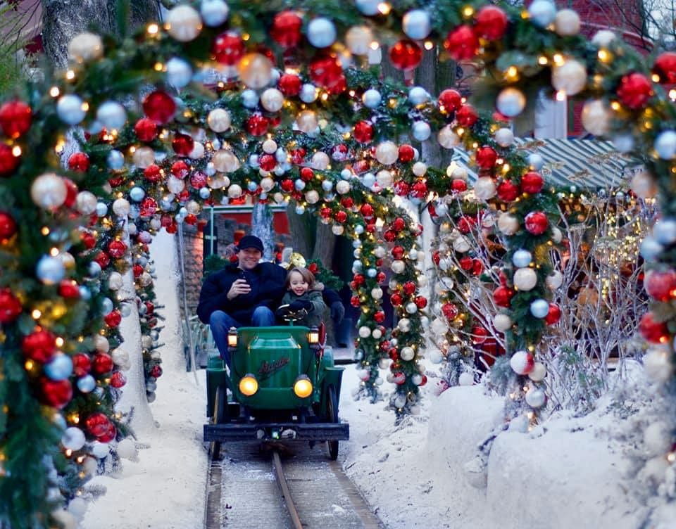 A dad and his young son ride a colorful Christmas train at Tivoli in Copenhagen, one of the best places for a December vacation with kids.