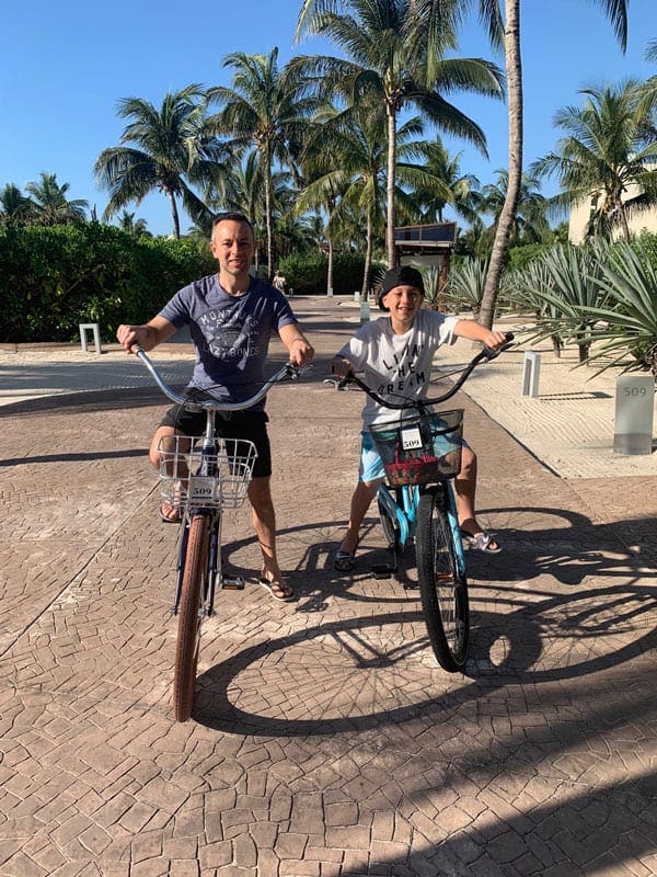 Father and son ride bikes through Rosewood Mayakoba.