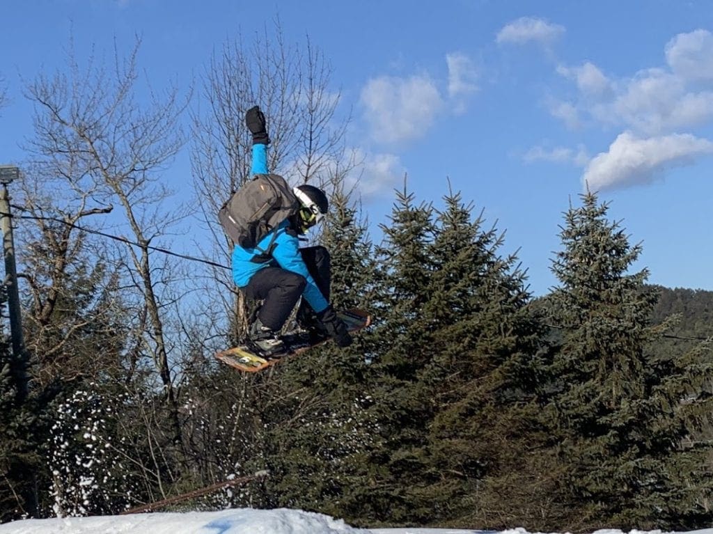A young boy takes a huge jump off a snowboard hill at Blue Mountain, one of the best ski resorts near NYC for families.