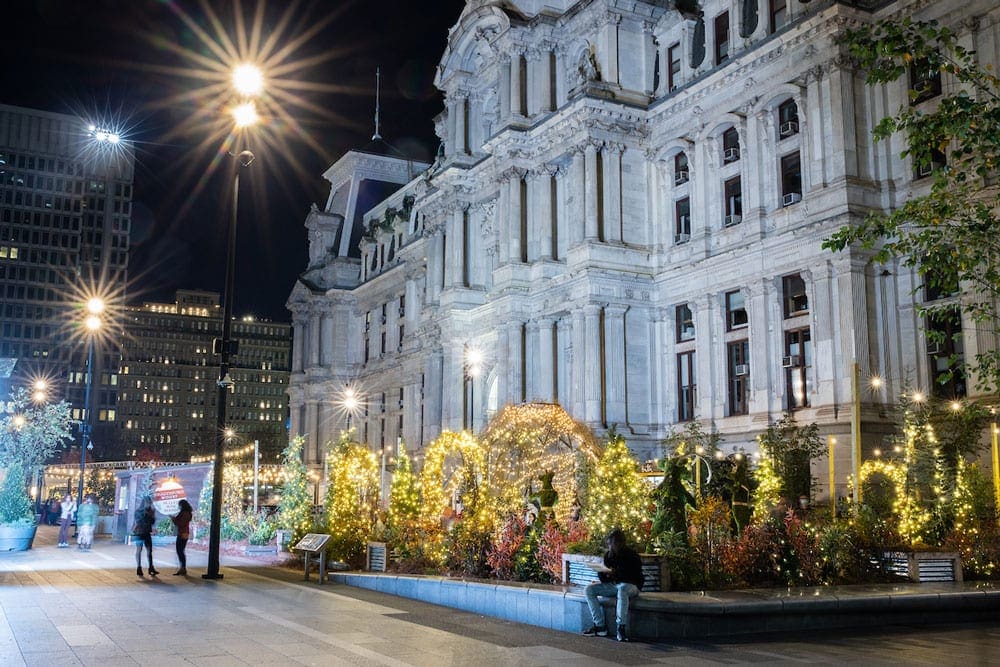 Dithworth Park outside of the City Center, one of the best things to do in Philadelphia with kids this winter, featuring evergreen trees with full holiday lights.