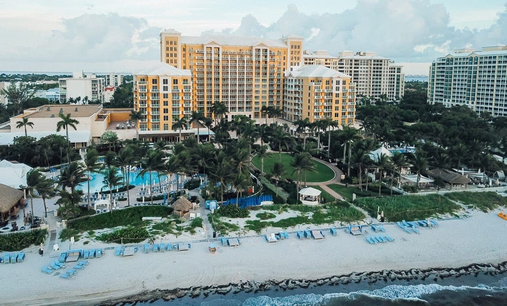 An arieal view of The Ritz-Carlton Key Biscayne, Miami, ones of the best family-friendly hotels in Miami, featuring white sand beaches, tall buildings, and palm trees.