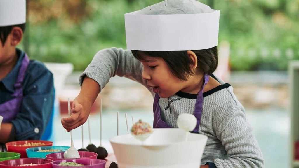 A young child, wearing a chefs hat, makes a cake pop at Grand Hyatt Playa del Carmen, one of the best resorts in Playa del Carmen.