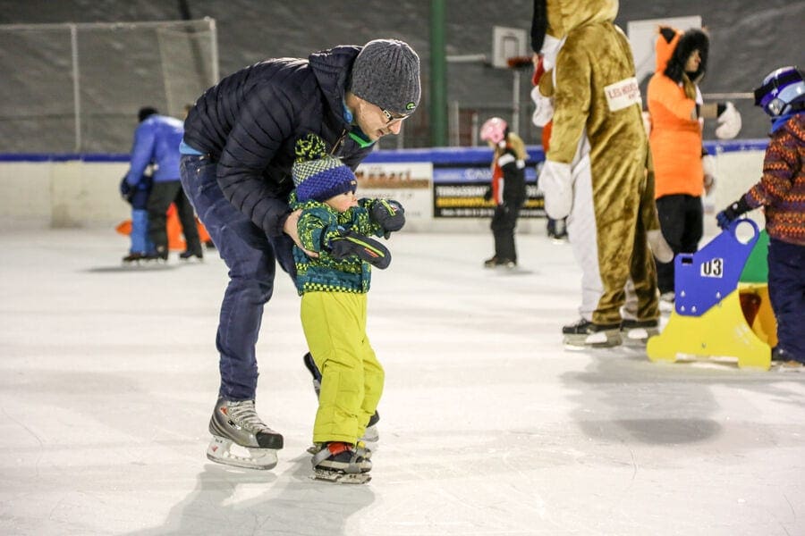 A dad holds on to his young toddler as they learn how to ice skate in Charmonix, , one of the best things to do in Chamonix with kids in Winter.