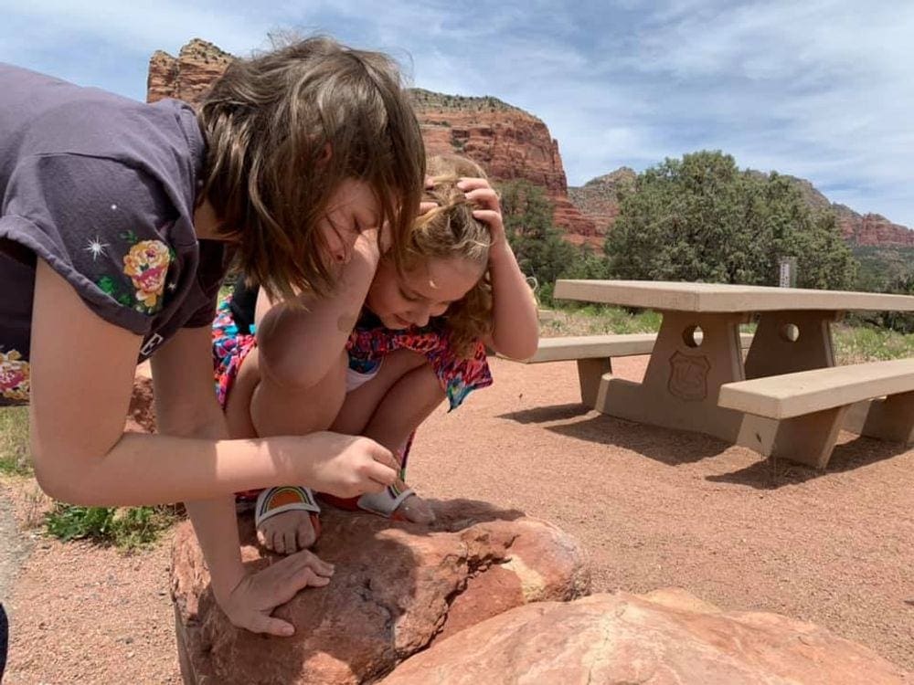 Two young girls look at an animal on the rocks in Sedona.