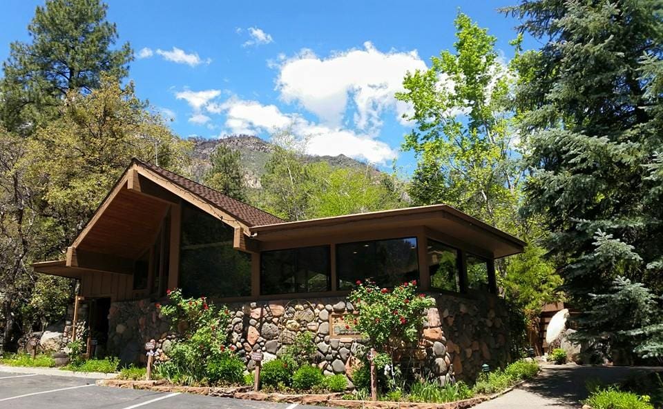 The entrance of Junipine Resort, one of the best hotels in Sedona for families, featuring lush greens and a blue sky.