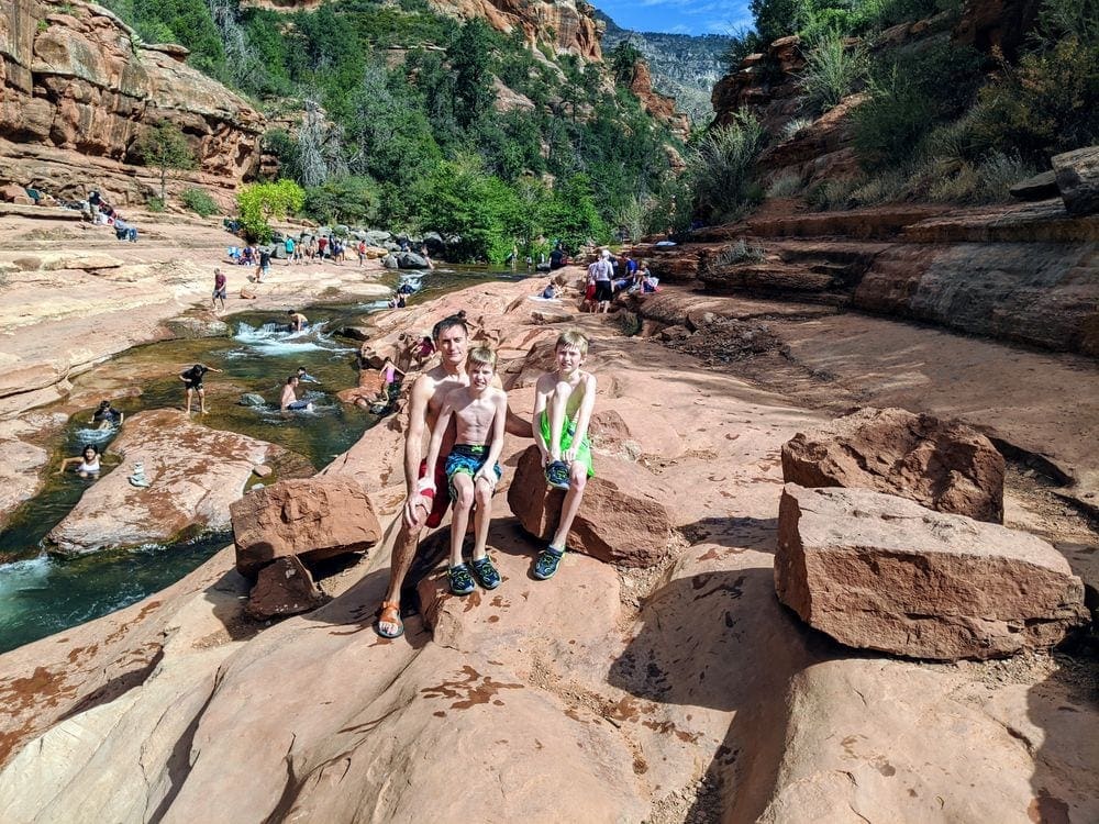 Kids climbing on rocks at Slide Rock State Park, one of the best places to visit on a Grand Canyon itinerary for families. 