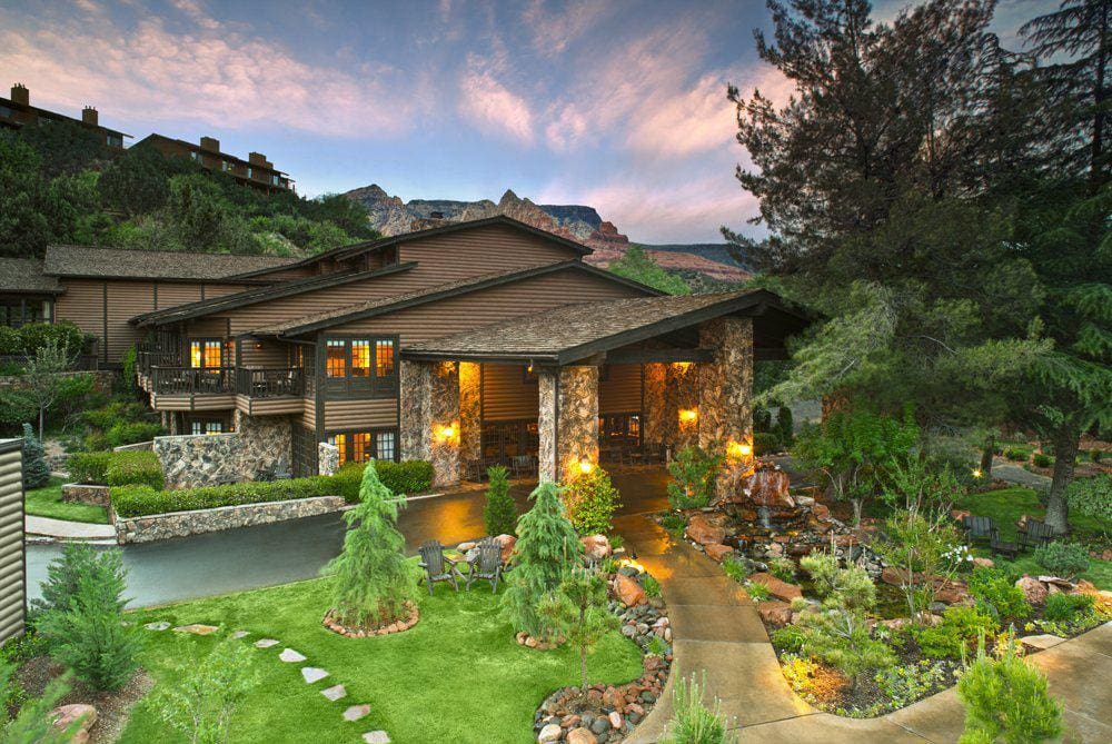 The entance to L’Auberge de Sedona, one of the best hotels in Sedona for kids. Featuring lush landscaping and a bright blue sky.