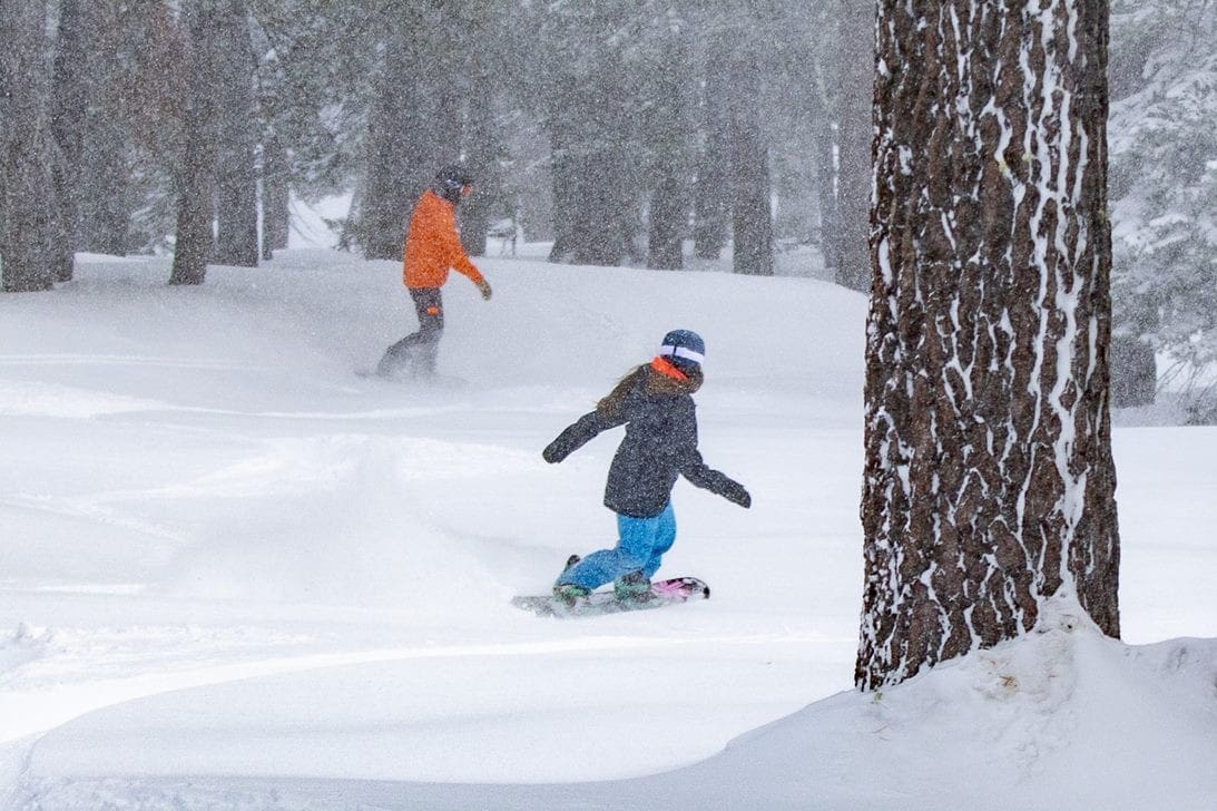 Two snowboarders curve down slopes at Northstar California Resort, one of the best ski resorts in the United States for families.