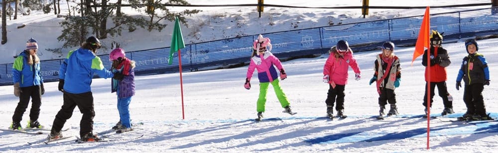 Two ski instructors look on at several kids standing on skis along a line at Massanutten Resort, one of the best options for skiing near DC with kids.