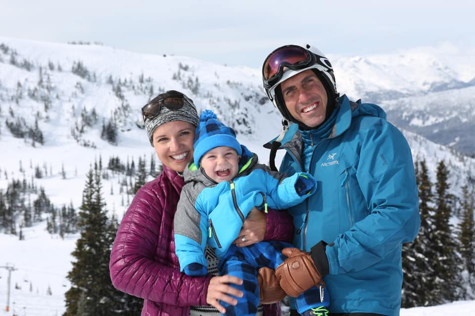 Family of three standing together, in full ski gear, while exploring a Whistler ski slope together.