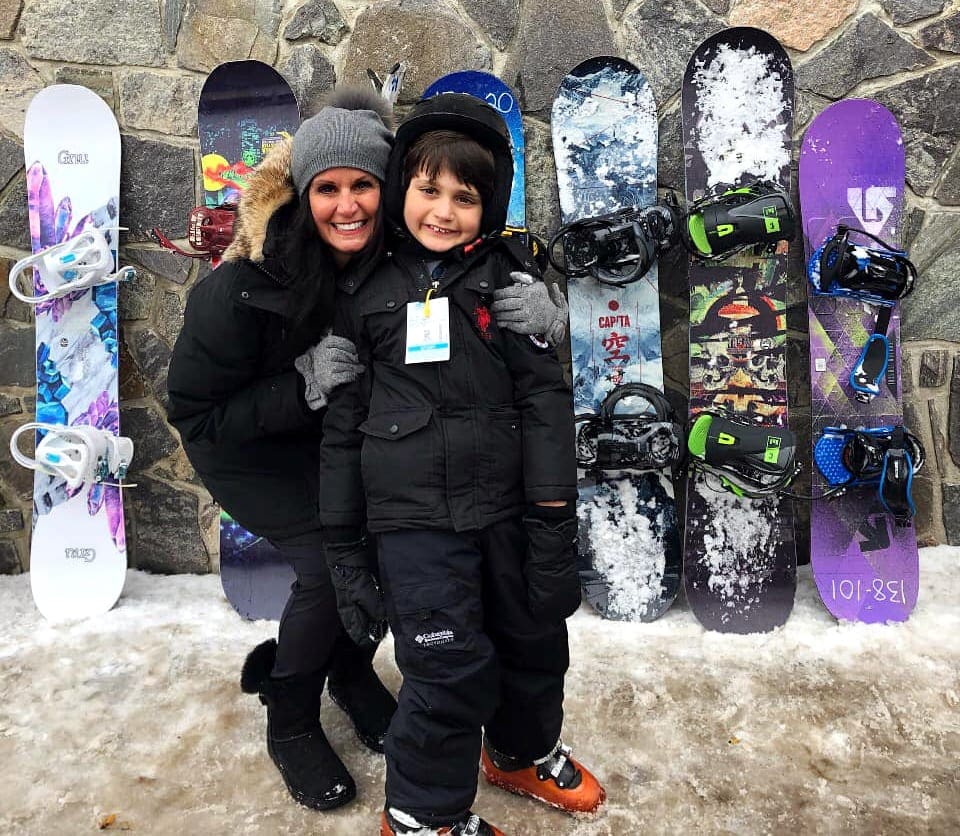 A mom hugs her young son in front of a series of colorful snowboards at Mount Snow in Vermont.