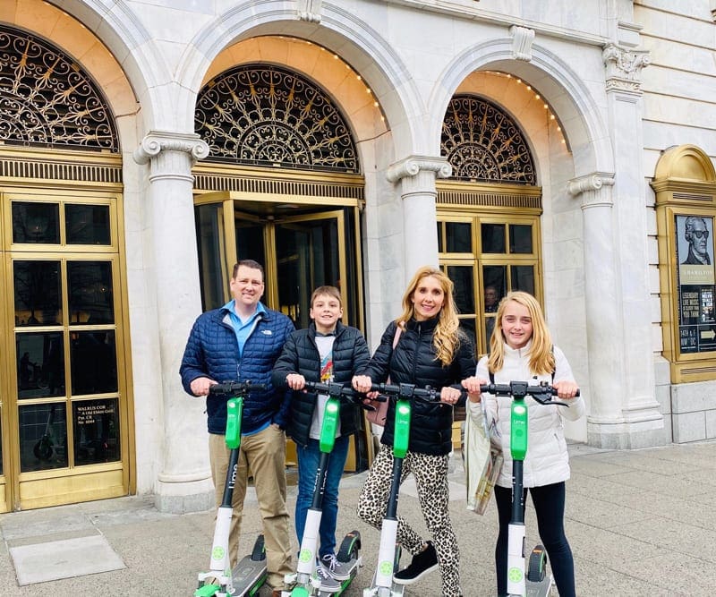 A family of four outside the hotel ready to explore Washington DC in scooter.