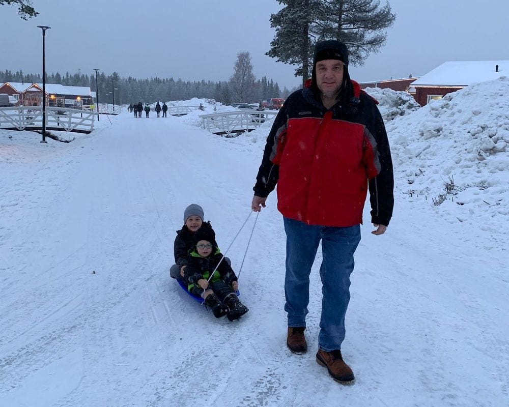 A dad pulls his two boys on a sled on a winter day.