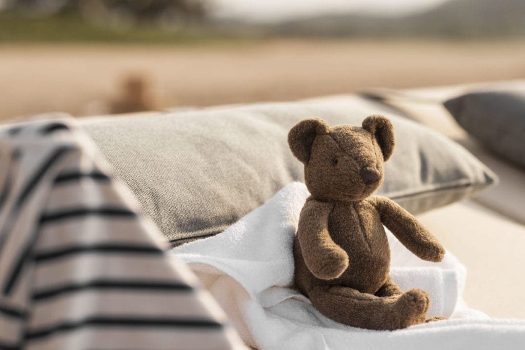 A teddy bear sits on a made bed at One&Only Mandarina, one of the best resorts in Mexico for families.