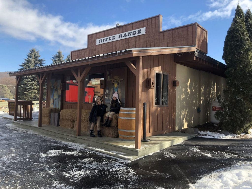 Two kids pose in front of a building at Rocking Horse Ranch, one of the best family resorts near NYC for a winter getaway.