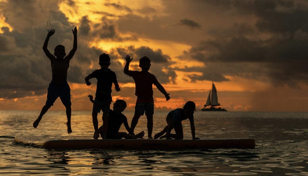 Five kids play at suset one the water off the beach at The Westin Grand Cayman Seven Mile Beach Resort & Spa.