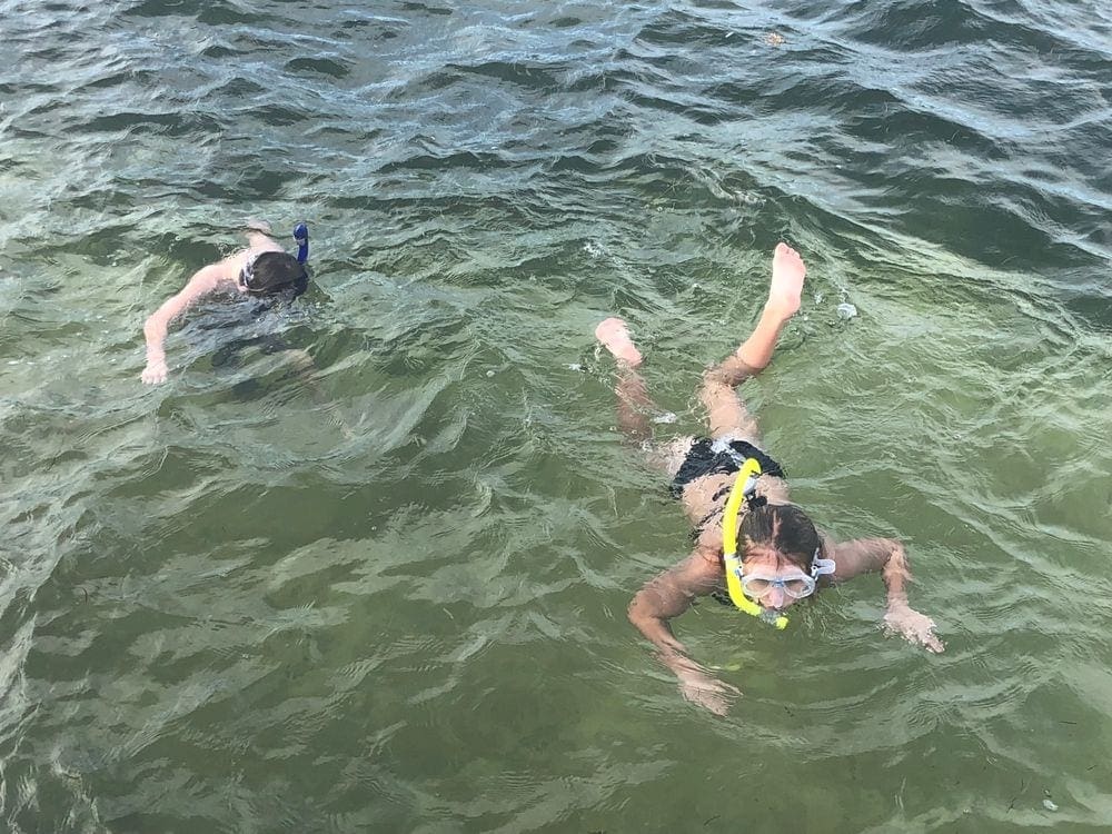 Two kids snorkel along the surface of the water in Belize.