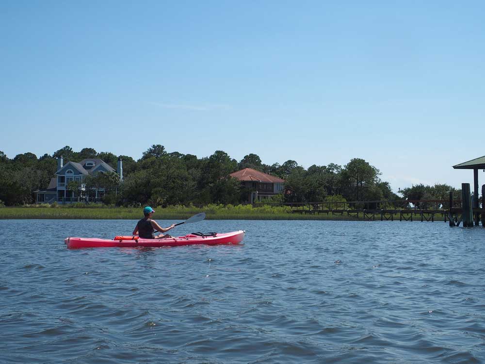 Person in red kayak in blue water in Amelia Island, Florida, one of the best places to stop on an NYC to Miami itinerary for families!