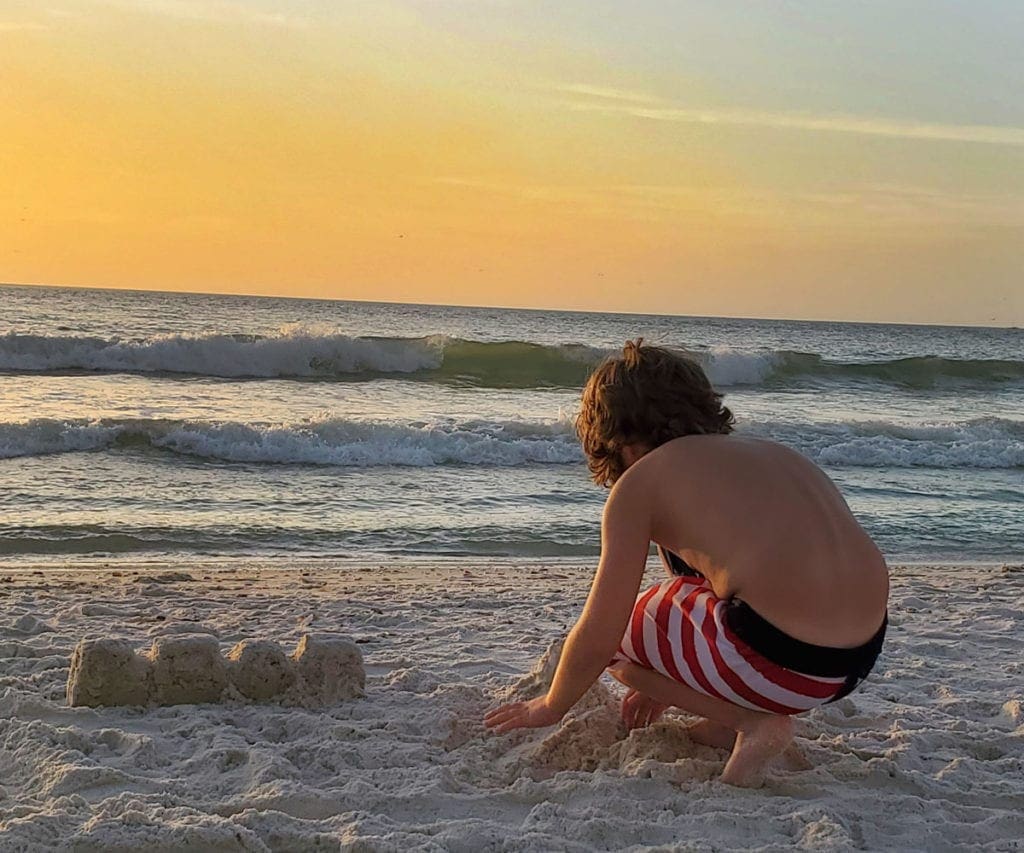 Boy on the beach at sunset in Naples.