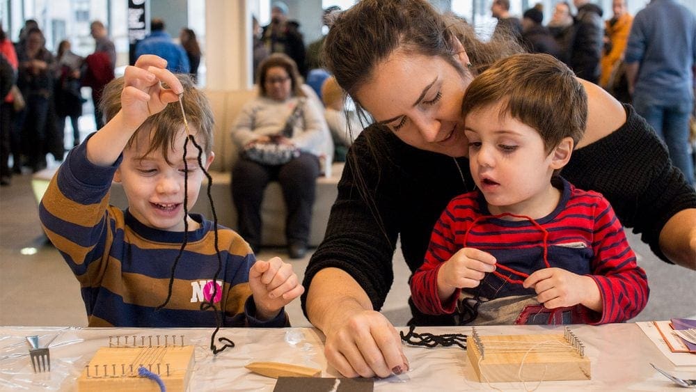 Two kids sit with their mom at an interactive activity at the Pointe-à-Callière, cité d'archéologie et d'histoire de Montréal.