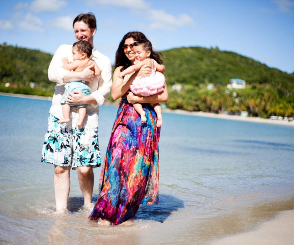 Family with twin babies standing in crystal blue water in Antigua.