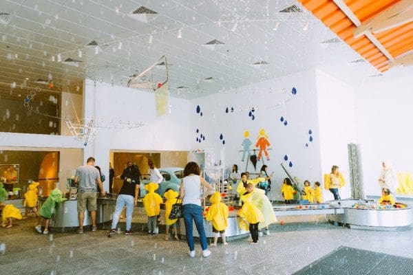 Several kids and parents play at a water table in an exhibit at Kidzania.