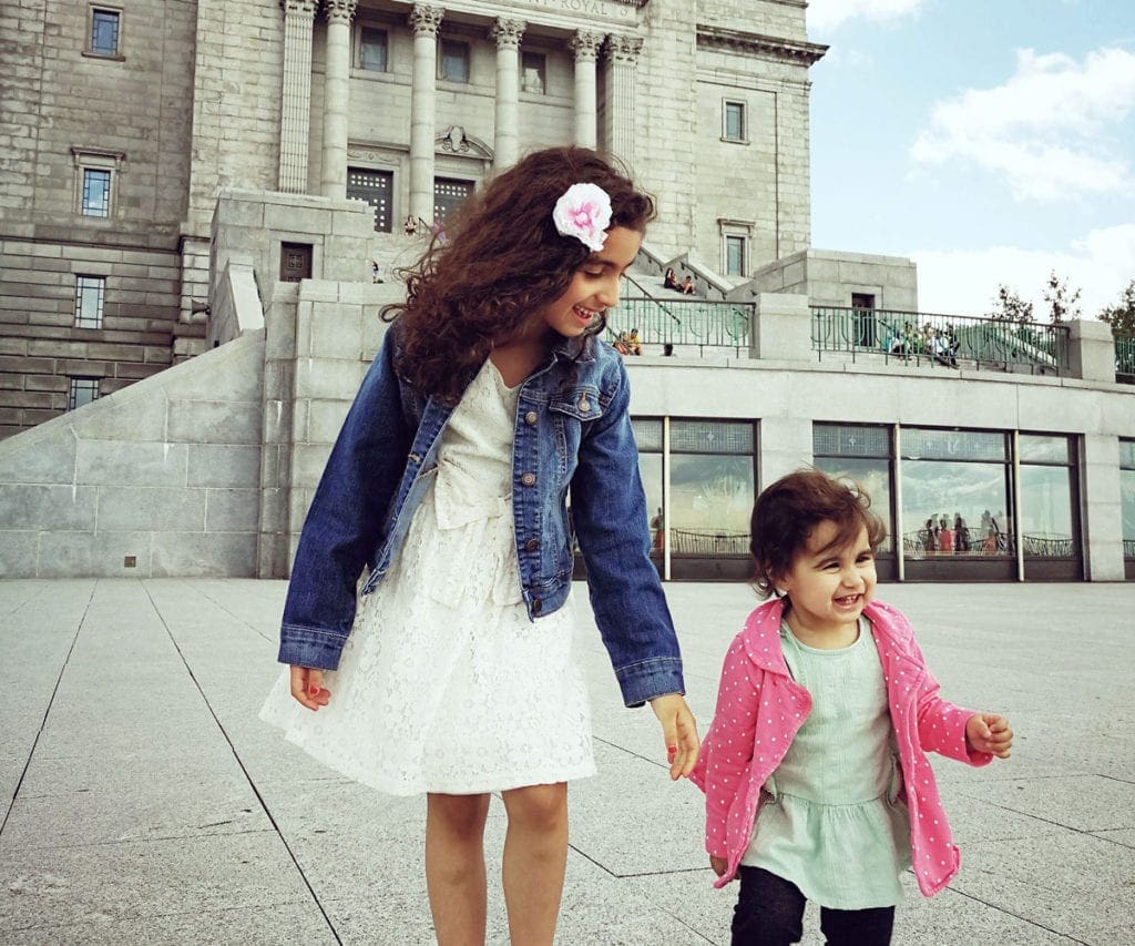 Pre-teen and toddler girls holding hands and waking in Montreal.