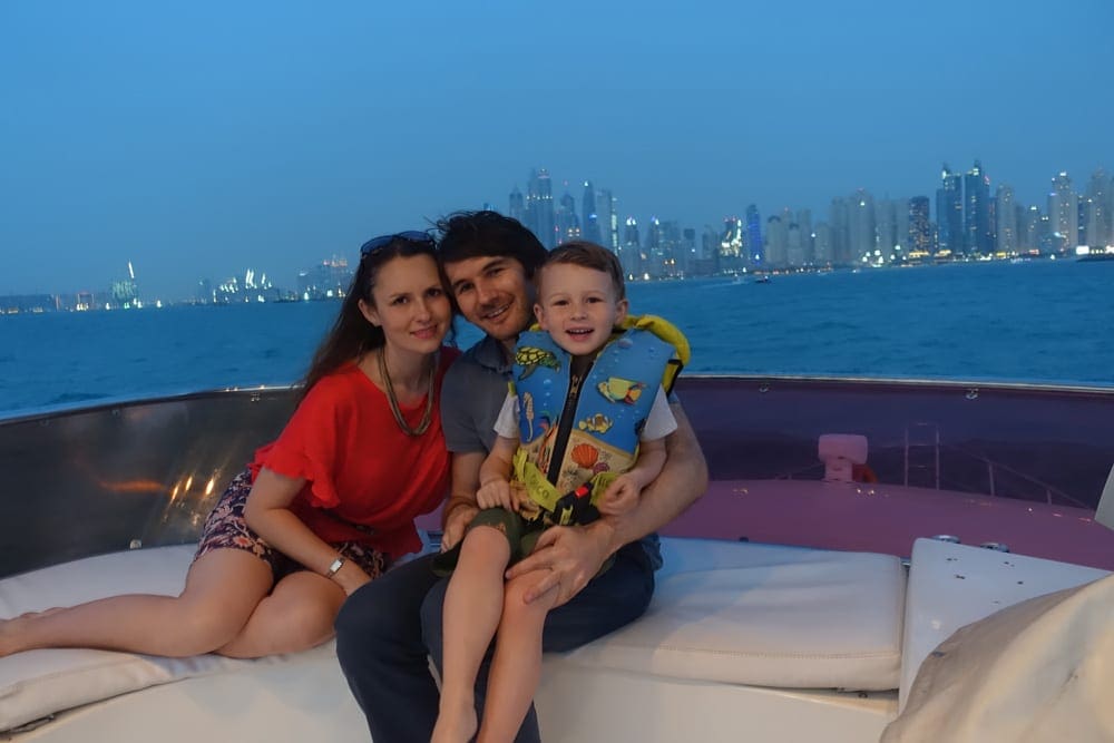 Two parents snuggle with their toddler while enjoying a boat tour in the marina.