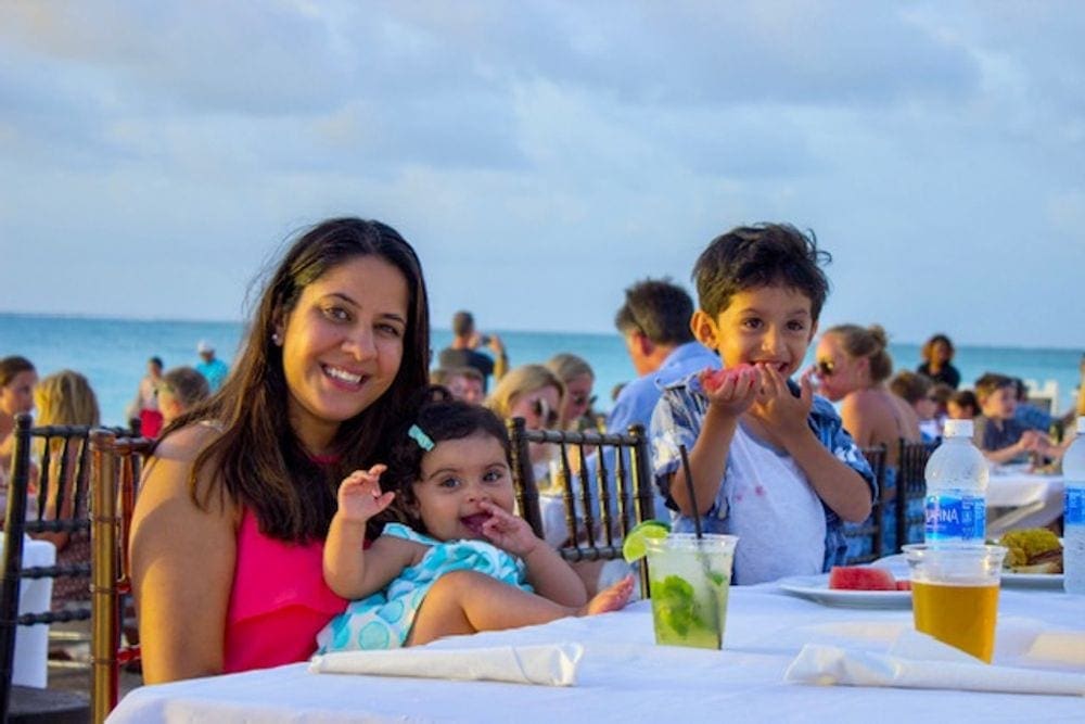 A mom and two kid enjoy a fun meal on the beach at The Somerset On Grace Bay in Turks & Caicos.