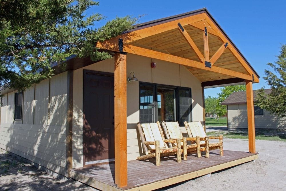 A cabin with three wooden chairs at Cedar Pass Lodge, the perfect place to stay on your Family-Friendly Itinerary to the Badlands.