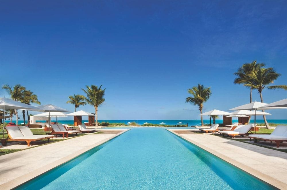 A long pool nestled between loungers with umbrellas at Grace Bay Club.