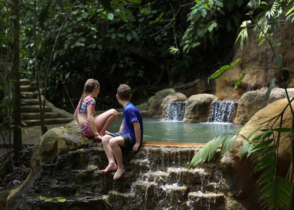 Two kids sit along a hot spring in Costa Rica.
