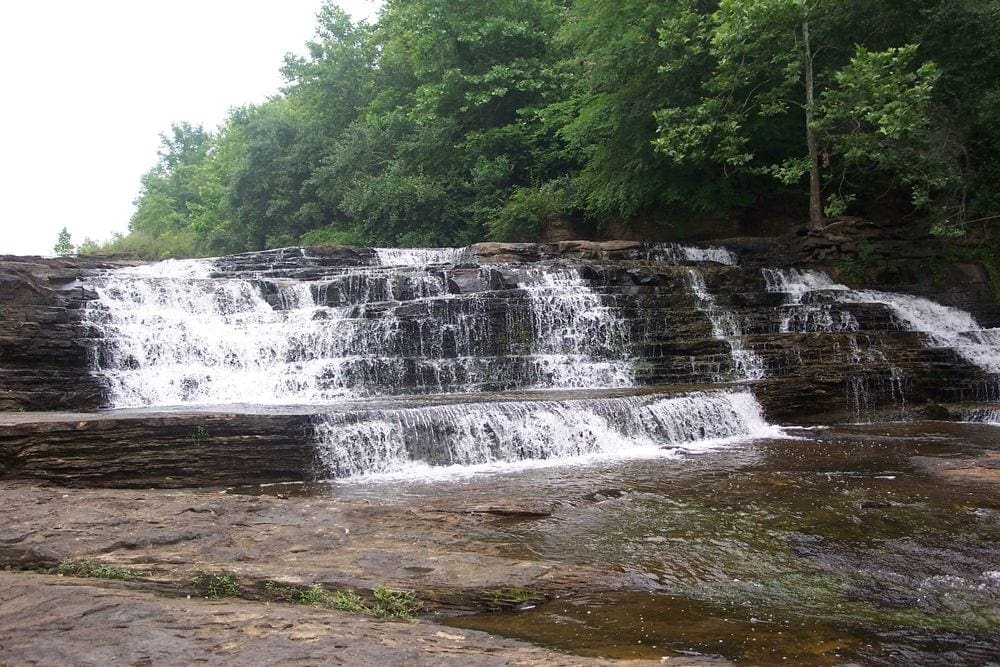 A waterfall spills over a small rock formation at Kinkaid Lake, one of the best places to visit in Southern Illinois for families.