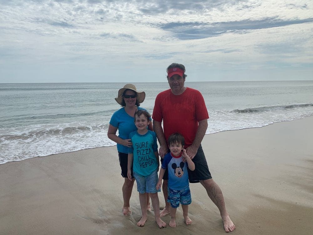 A family of five stands on a beach in the Outer Banks on an overcast day.