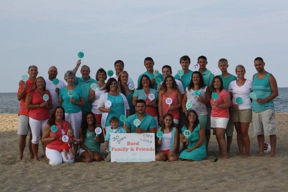 A large, multigenerational family poses on Rehoboth Beach capturing a family reunion.