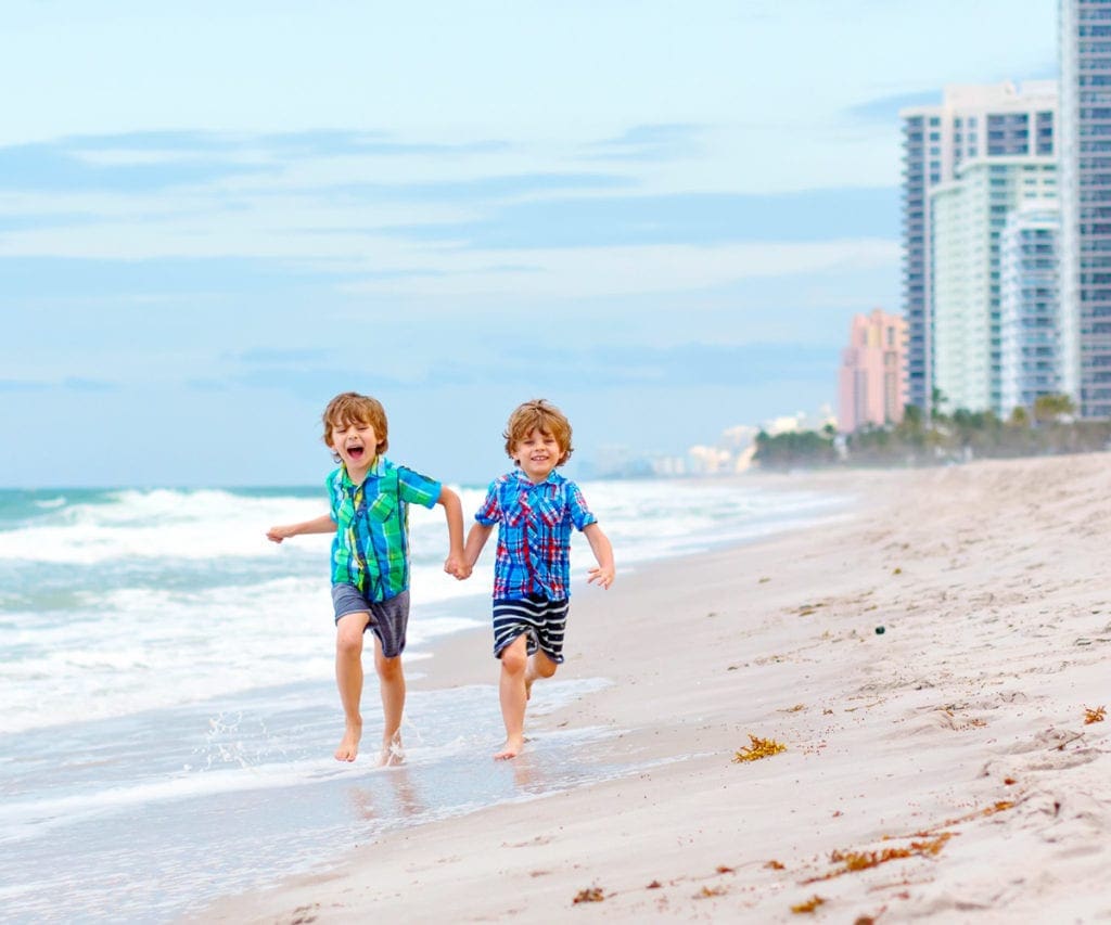 Two Buys running on the Beach in Miami, one of the best places for an East Coast road trip for families. 