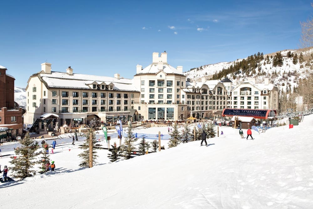 A few skiers meander the grounds on a sunny, winter day at Park Hyatt Beaver Creek Resort and Spa, one of the best best ski in ski out resorts in Colorado.
