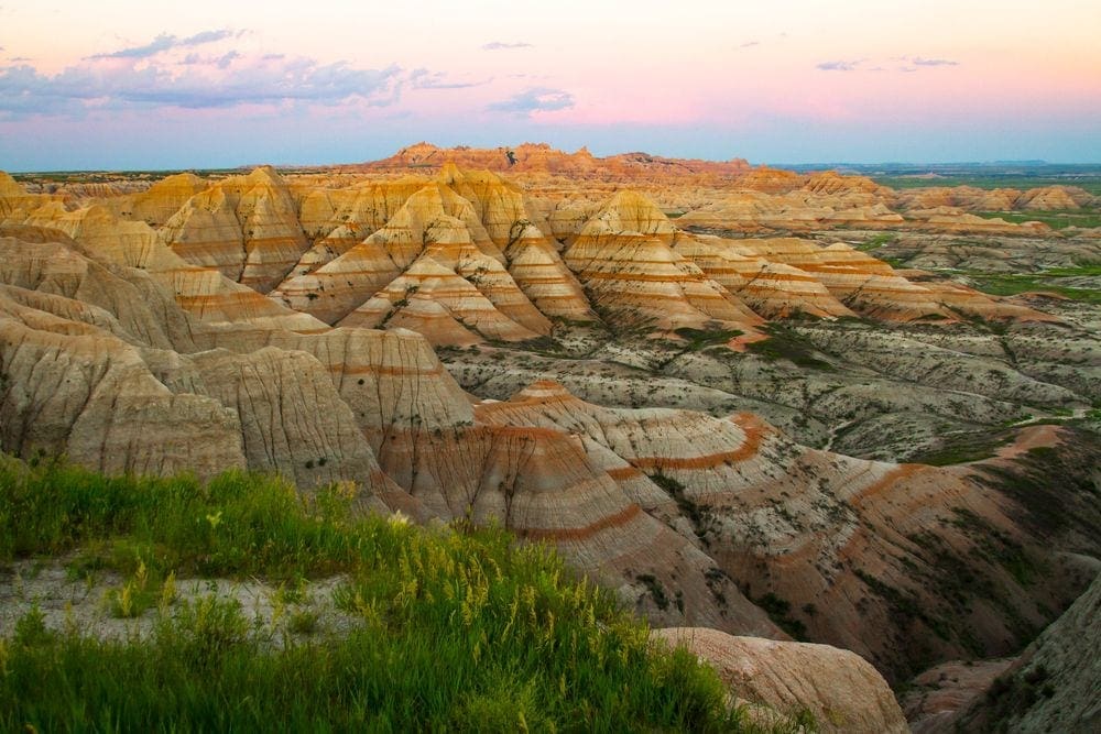 A scenic view of painted rock formations in the Badlands National Park at sunset.